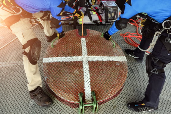 2 men holding the handles on a metal hatch to open it