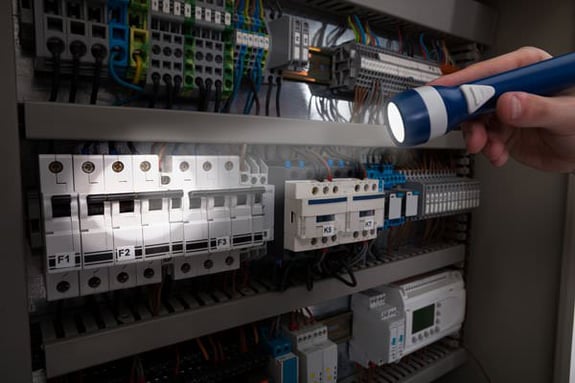 technician using a flashlight on an electrical panel