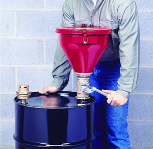 worker using funnel on storage drum